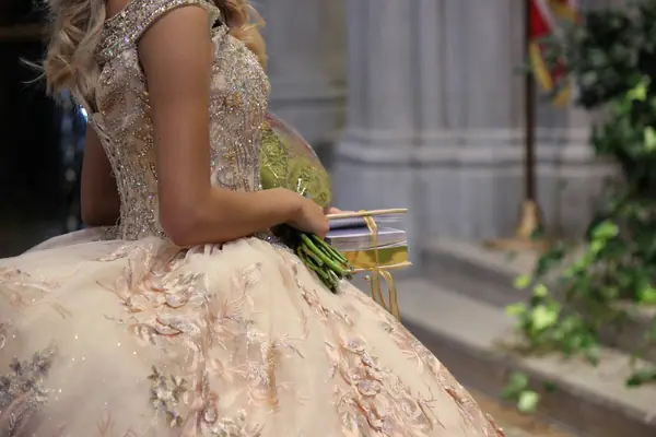 Quinceañera con vestido de gala y ramo de flores